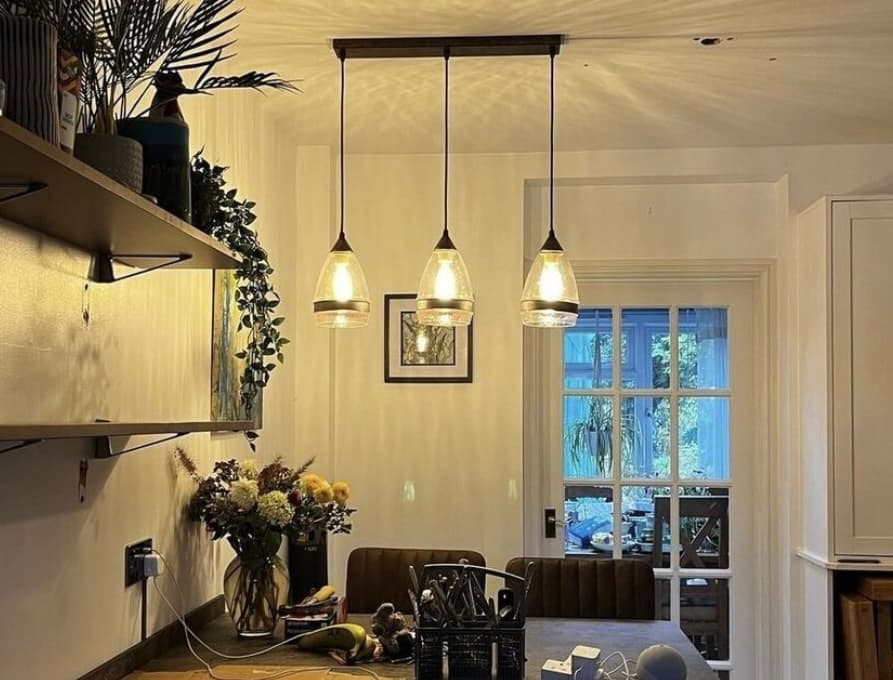 Three warm pendant lights installed above a dining table